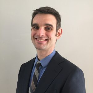 Professional headshot of Casey Conlin wearing a suit and tie.